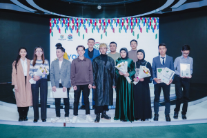 Gruppe von Menschen auf einer Bühne mit Blumensträußen und Urkunden, vor dem Hintergrund einer 'Youth Solar Awards 2019'-Plakate.