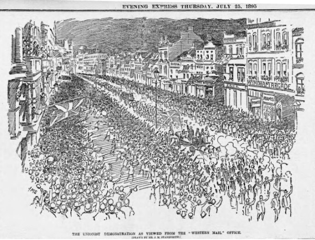Schwarze und weiße Zeichnung einer Menge, die eine von Gebäuden gesäumte Straße entlanggeht, mit Text oben und unten, der "Die Unionistendemonstration aus der Sicht des Western Mail Office" lautet.