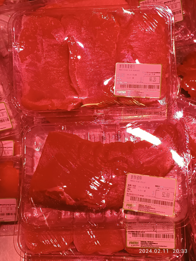 Gefrorene Fleischwaren in Plastikbehältern mit Etiketten in einer Vitrine.