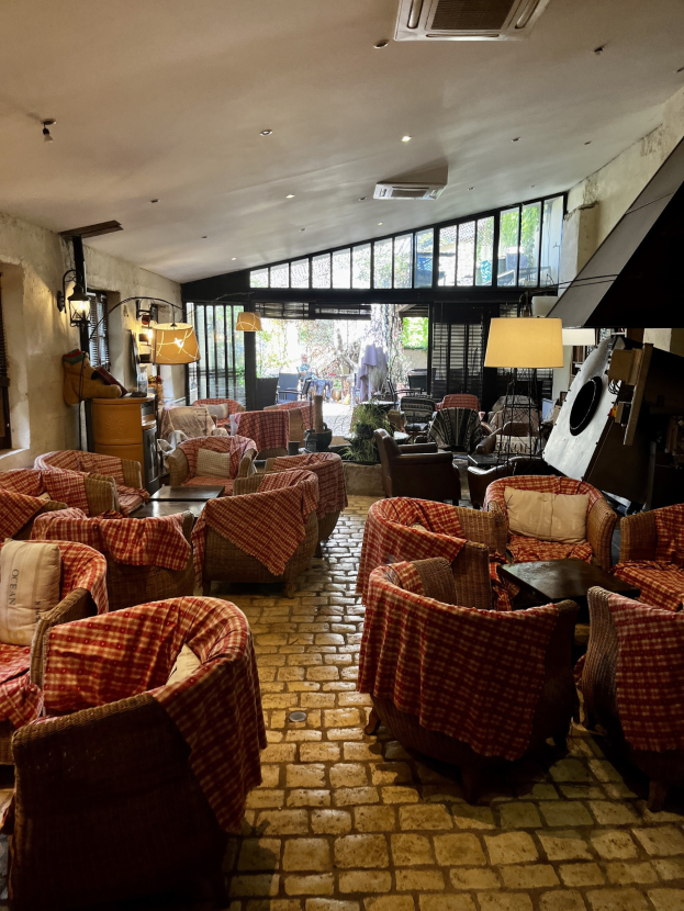 Ein geräumiger Eingangsbereich mit Reihen von Stühlen und Tischen, gepolsterte Sofas, Wandlampen, Deckenklimaanlage und Glasfenster an der Rückseite des Hotel de Ville.