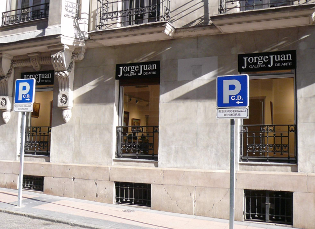 Ein mehrstöckiges Gebäude mit Fenstern, Geländern, Türen und Säulen, das Werbetafeln auf Pfählen entlang des Gehwegs und sichtbare Innenobjekte zeigt, die auf eine belebte städtische Umgebung hinweisen.