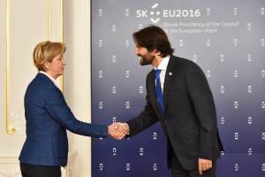 Bundeskanzlerin Angela Merkel und Bundespräsident Joachim Gauck schütteln sich die Hand und lächeln vor einer Wand mit einem "EU-Gipfel"-Schild und einer Tür.