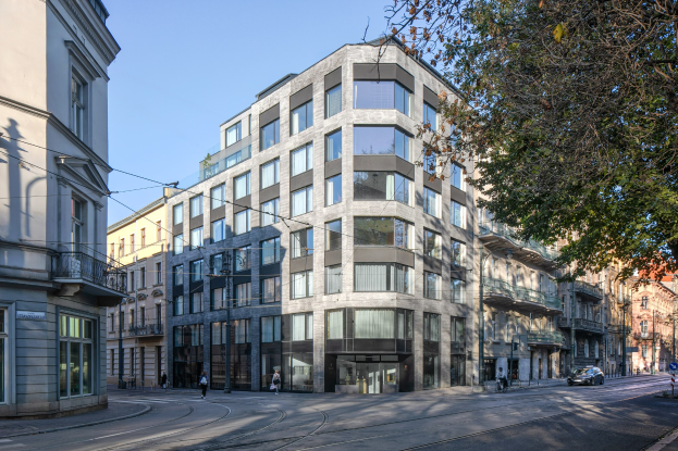 Großes modernes Bürogebäude mit vielen Fenstern, umgeben von Straßeninfrastruktur, Fahrzeugen, Fußgängern, Bäumen und einem bewölkten Himmel.
