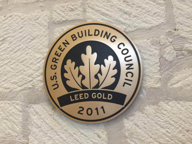 Logo der U.S. Green Building Council an der Außenseite eines Gebäudes, das ein grünes Schild mit einer weißen Umrandung, schwarzer Schrift und einem umgebenden Lorbeerkranz zeigt.