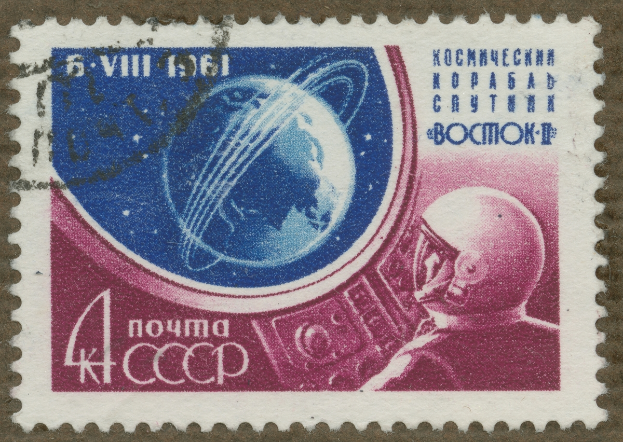 Eine Briefmarke mit einem Mann im Weltraumanzug mit entschlossener Miene, umgeben von der fettgedruckten, weißen Schrift "Marke".