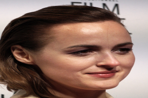 Natalie Portman auf dem Berlin Film Festival, strahlend in einem cremefarbenen Kleid, mit einer weißen Tafel im Hintergrund.