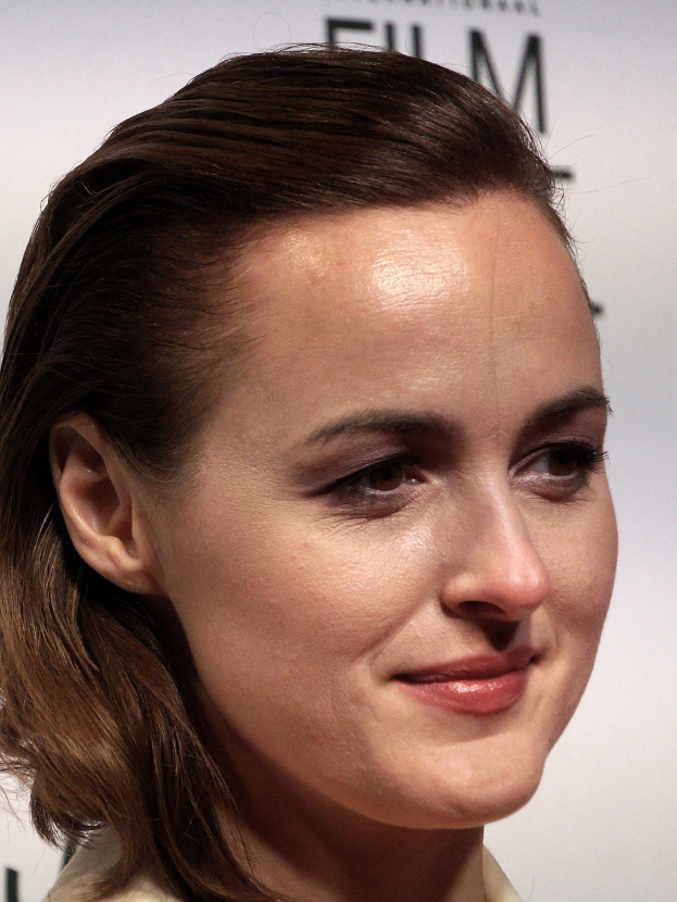 Natalie Portman auf dem Berlin Film Festival, strahlend in einem cremefarbenen Kleid, mit einer weißen Tafel im Hintergrund.