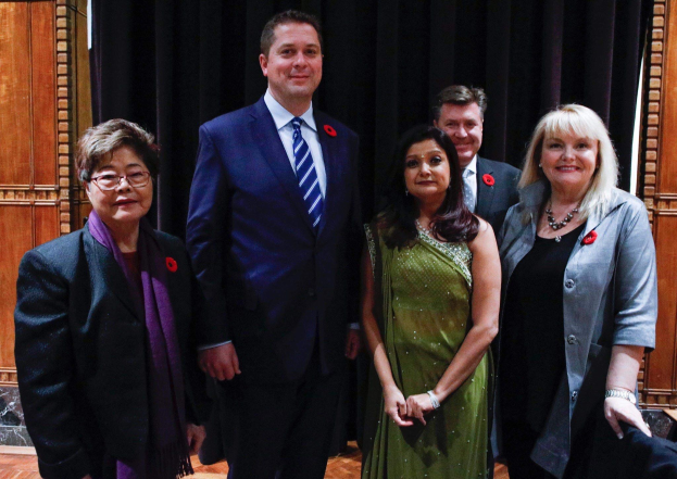 Gruppe von Menschen vor schwarzem Vorhang mit einer hölzernen Wand im Hintergrund, die scheinbar Mitglieder der FDP bei einer Versammlung sind.