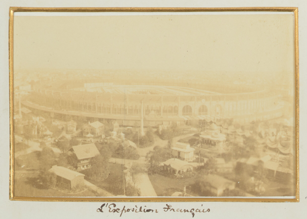 Schwarzes und weißes Foto eines Stadions, umgeben von Geb├Ąuden, B├Ąumen und Strommasten, mit Text unten.