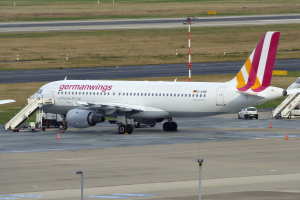 Germanwings Airbus A320-200 am Frankfurt Airport geparkt mit Bodenfahrzeugen, Verkehrskegeln, Versorgungsmasten und Rasenfläche im Hintergrund.