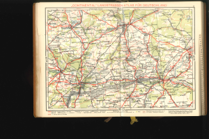 Ein aufgeschlagenes Buch mit einer detaillierten Deutschlandkarte, die Straßen und Autobahnen zeigt, vor einem schwarzen Hintergrund.