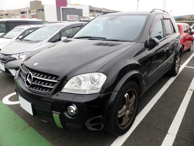 Schwarzer Mercedes-Benz ML 350 CDI Blueefficiency auf einem Parkplatz mit Gebäuden, Polen, Bäumen und einem klaren blauen Himmel im Hintergrund geparkt.