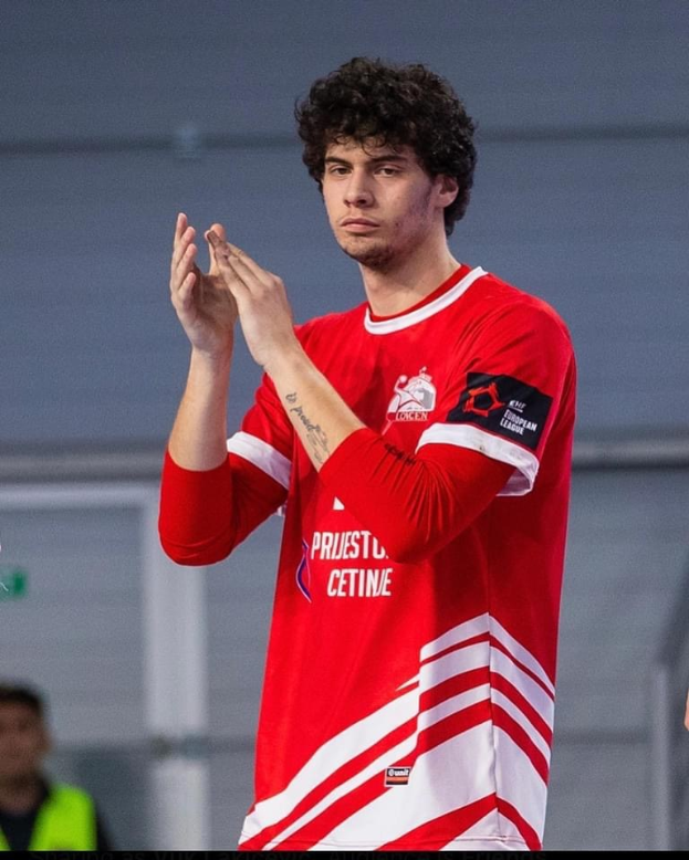 Ein Mann in einem roten und weißen T-Shirt klatscht in den Händen im Vordergrund mit einer anderen Person und einer Wand im Hintergrund, mit dem Text "Copenhagen Futsal Club - Foto 1" unten.