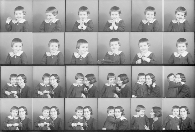 Schwarzes und weißes Foto einer Gruppe von Kindern mit einer Frau in der Mitte, die ein Baby hält und beide strahlende Gesichter zeigen.