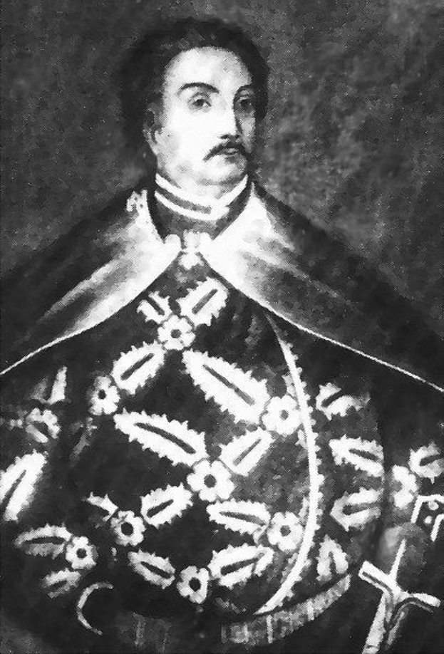 Schwarzes und weißes Foto von Papst Johannes Paul II. in Priesterkleidung, der eine schwarze Robe mit weißem Kragen und Manschetten trägt und mit ernster Miene und direktem Blick die Hände verschränkt.