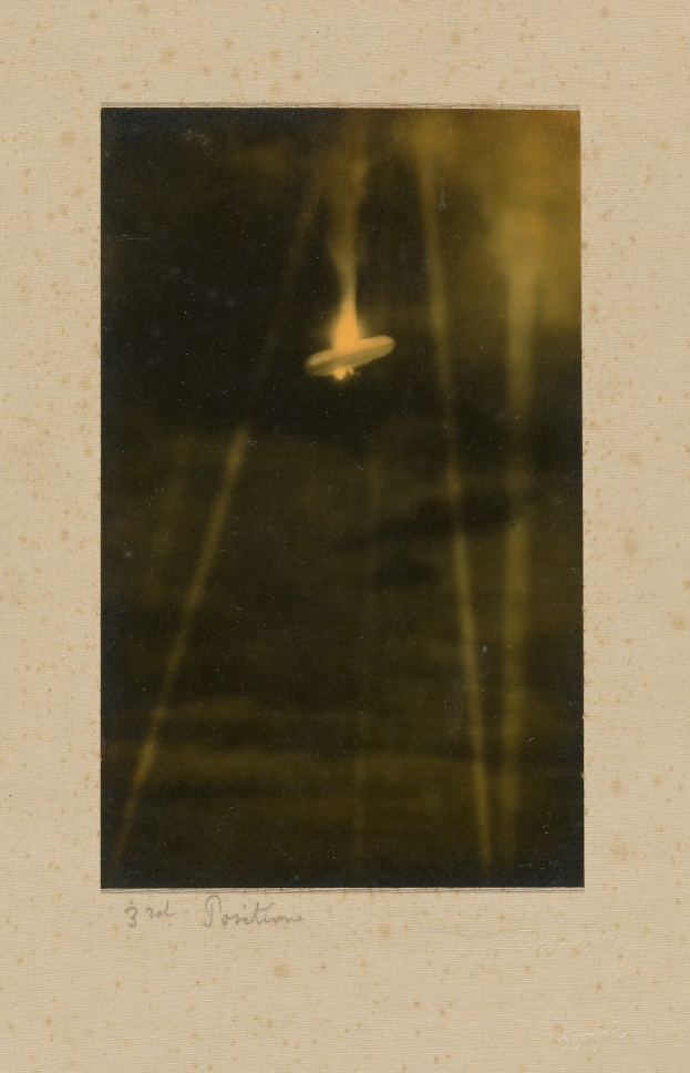 Schwarzes und weißes Foto eines unbekannten fliegenden Objekts über einem Gewässer mit Text unten.